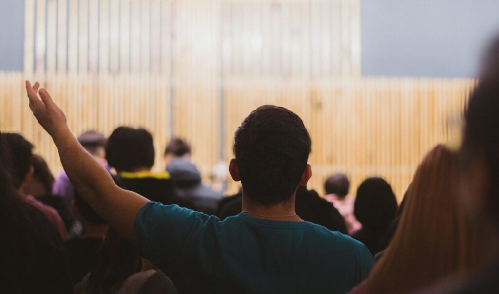 Congregation worshiping together in church sanctuary with raised hands, showing the importance of fellowship and community in spiritual growth