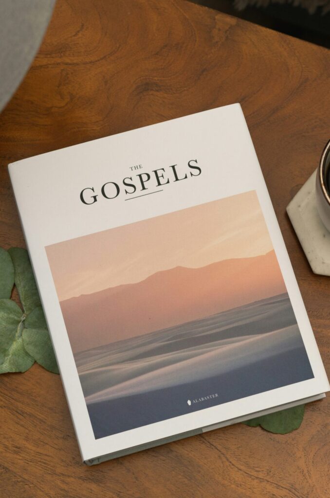 A book titled “The Gospels” placed on a wooden table next to a cup of coffee, symbolizing peaceful reflection and reading the story of Jesus in chronological order.