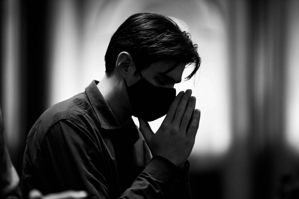 A man in a room with His hands together to show the importance of prayer to walk in the Spirit. 